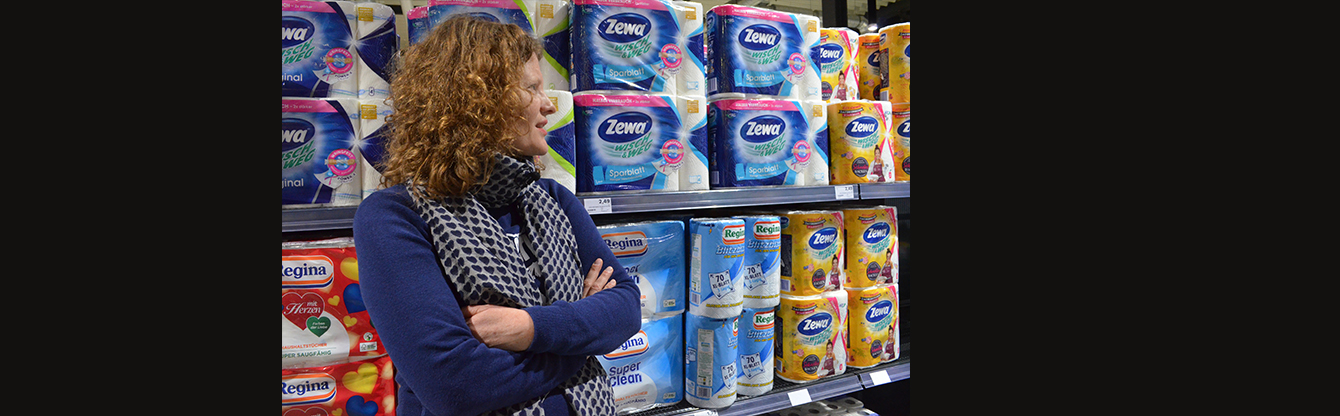 Foto von Stephanie Senge, die vor einem Regal im Supermarkt steht in welchem Küchentücher stehen.